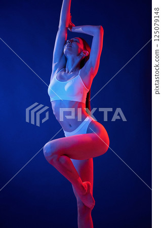 Blue and red colors. Young woman in underwear is in the studio with neon lights Blue and red colors. Young woman in underwear is in the studio with neon lights 125079148