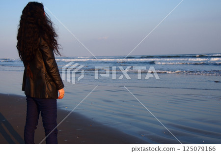 Woman standing on the beach at sunset 125079166