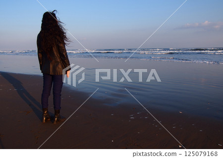 Woman standing on the beach at sunset Woman standing on the beach at sunset 125079168