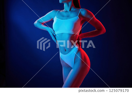 Taking a closer look. Young woman in underwear is in the studio with neon lights 125079170