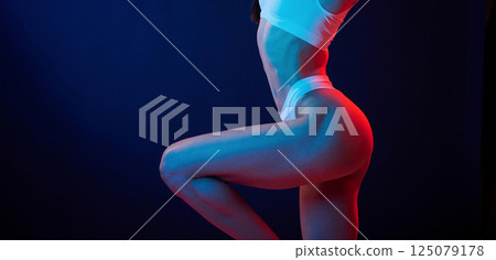 Beautiful slim body type. Young woman in underwear is in the studio with neon lights Beautiful slim body type. Young woman in underwear is in the studio with neon lights 125079178