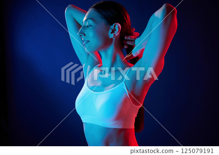 Feeling relaxed. Young woman in underwear is in the studio with neon lights Feeling relaxed. Young woman in underwear is in the studio with neon lights 125079191