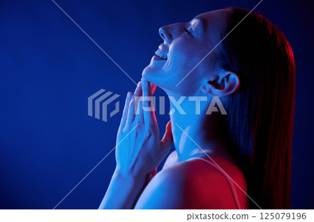 Happy and relaxed. Young woman in underwear is in the studio with neon lights Happy and relaxed. Young woman in underwear is in the studio with neon lights 125079196