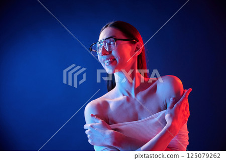 In eyewear. Portrait of young woman that is indoors in neon lighting 125079262