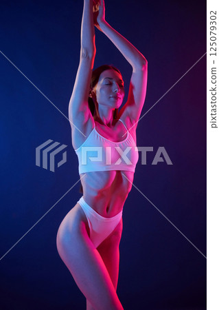 Tall and slender. Young woman in underwear is in the studio with neon lights 125079302