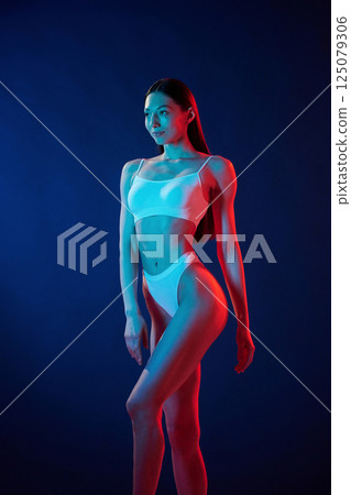 Tall and slender. Young woman in underwear is in the studio with neon lights 125079306