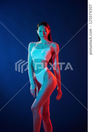 Diferent poses. Young woman in underwear is in the studio with neon lights 125079307