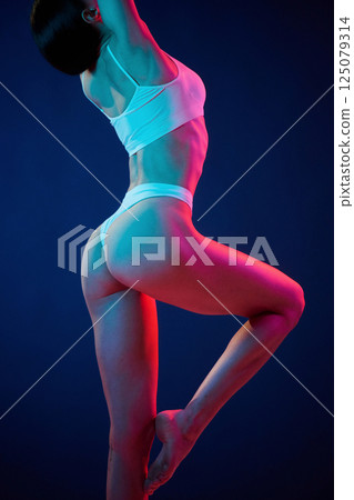 View from the side. Young woman in underwear is in the studio with neon lights 125079314