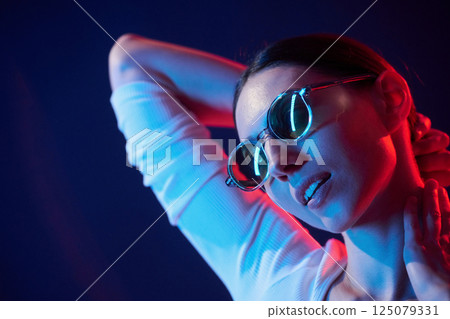Wearing glasses. Portrait of young woman that is indoors in neon lighting Wearing glasses. Portrait of young woman that is indoors in neon lighting 125079331