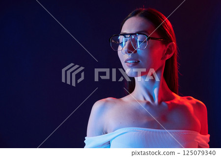 Beautiful look. Portrait of young woman that is indoors in neon lighting Beautiful look. Portrait of young woman that is indoors in neon lighting 125079340