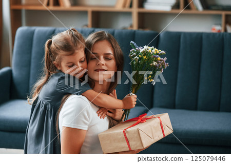 Gifts at mother's day. Young woman with her daughter is together at apartment Gifts at mother's day. Young woman with her daughter is together at apartment 125079446