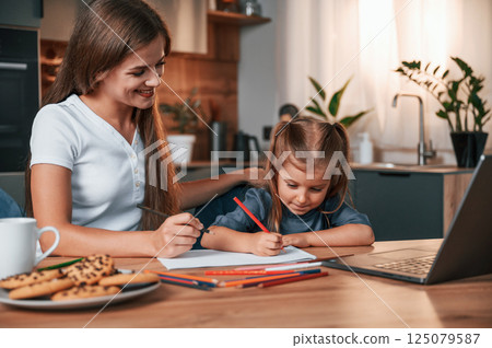 Learning how to draw. Young mother with her daughter is together at apartment Learning how to draw. Young mother with her daughter is together at apartment 125079587