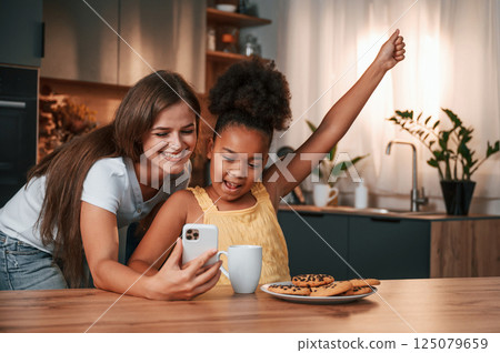 Making a selfie. Young mother with her daughter is together at apartment Making a selfie. Young mother with her daughter is together at apartment 125079659