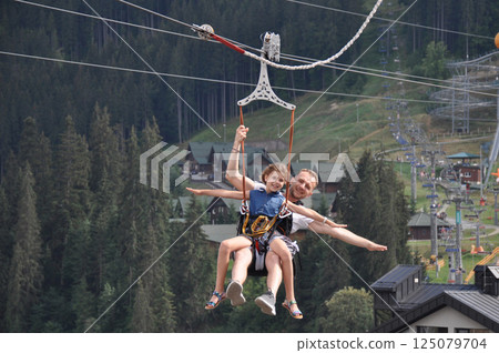 Happy father with his daughter is on the ski lift having fun and smiling. Majestic view of Carpathians Happy father with his daughter is on the ski lift having fun and smiling. Majestic view of Carpathians 125079704