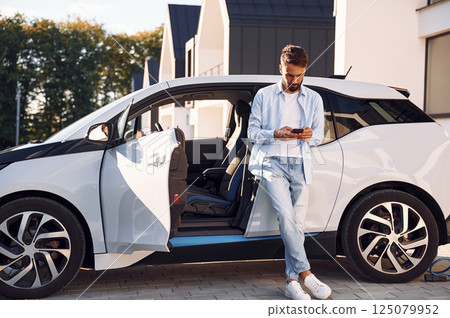 Young stylish man is with electric car at daytime 125079952