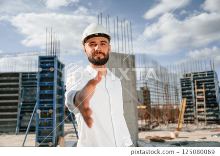Engineer extends his hand. Man in uniform is working on the construction site 125080069