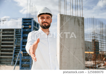 Engineer extends his hand. Man in uniform is working on the construction site Engineer extends his hand. Man in uniform is working on the construction site 125080070