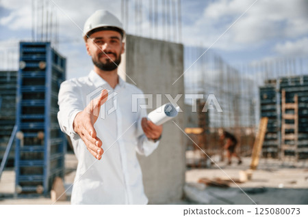 Engineer extends his hand. Man in uniform is working on the construction site 125080073