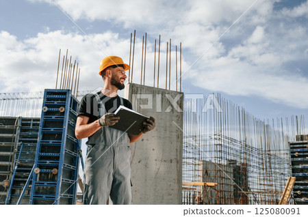 In hard hat, with notepad. Man in uniform is working on the construction site In hard hat, with notepad. Man in uniform is working on the construction site 125080091