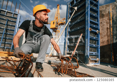 Metal pieces covered in rust. Man in uniform is working on the construction site 125080165