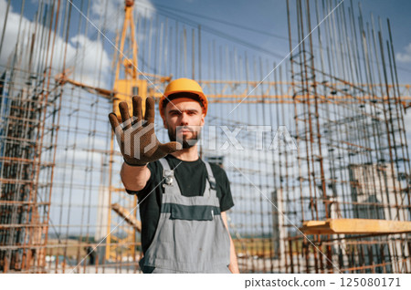 Closed area. Stop gesture. Man in uniform is working on the construction site Closed area. Stop gesture. Man in uniform is working on the construction site 125080171