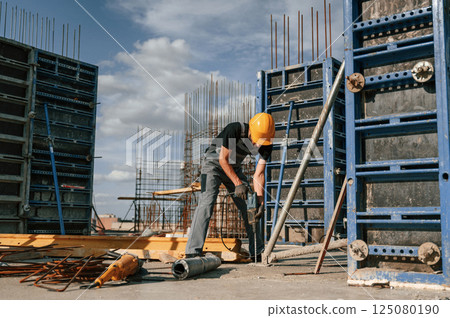 Using the drill. Man in uniform is working on the construction site 125080190