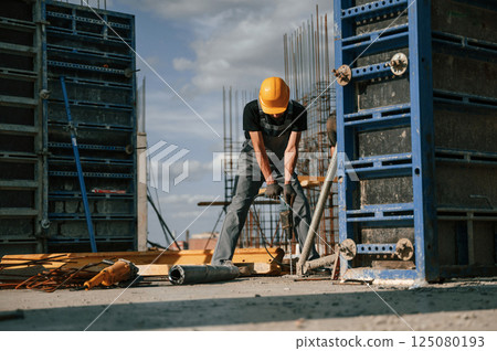 Using the drill. Man in uniform is working on the construction site Using the drill. Man in uniform is working on the construction site 125080193