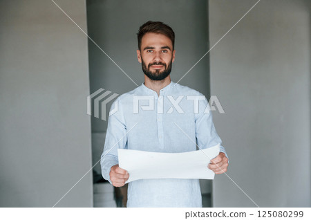 Holding and reading document. The man is making repairs in the apartment 125080299