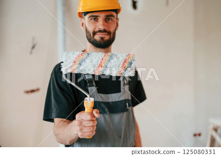 With painting roll. The man is making repairs in the apartment 125080331