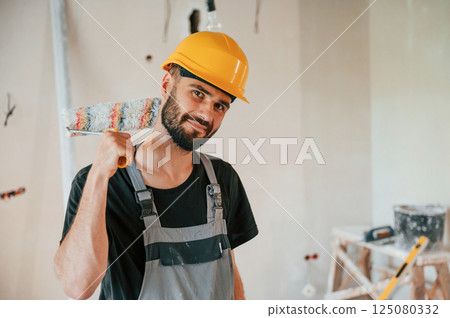 With painting roll. The man is making repairs in the apartment 125080332
