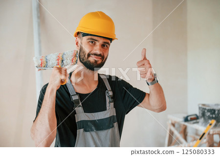 With painting roll. The man is making repairs in the apartment 125080333