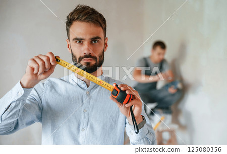 Two men is making repairs in the apartment together Two men is making repairs in the apartment together 125080356