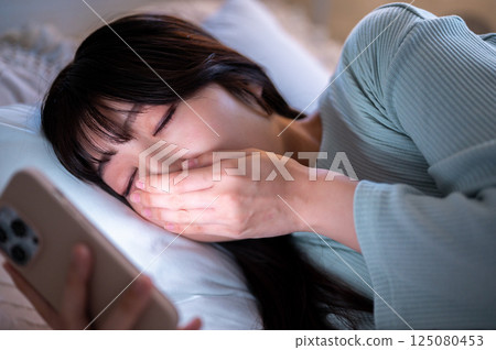 一位年輕女子深夜熬夜看智慧型手機 125080453