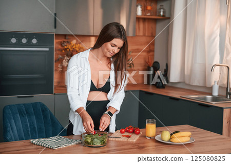 Preparing the salad on kitchen. Beautiful pregnant woman is indoors at home Preparing the salad on kitchen. Beautiful pregnant woman is indoors at home 125080825