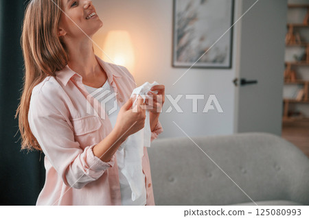 Cute little shirt. Beautiful pregnant woman is indoors at home Cute little shirt. Beautiful pregnant woman is indoors at home 125080993