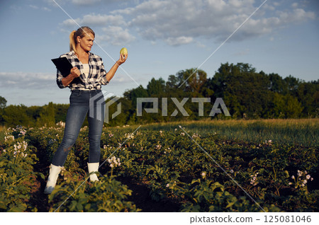 Quality control. WIth notepad and cabbage. Woman is on the agricultural field at daytime 125081046