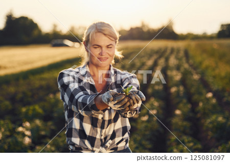 Artichoke is in hands. Woman is on the agricultural field at daytime 125081097