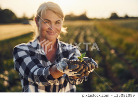 With an artichoke. Woman is on the agricultural field at daytime 125081099