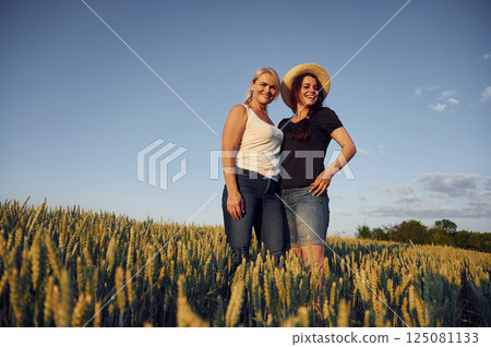 Two women standing on the agriculture field with growing wheat 125081133
