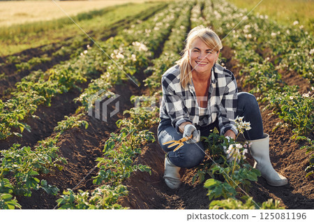 Sitting and smiling. Woman is on the agricultural field at daytime Sitting and smiling. Woman is on the agricultural field at daytime 125081196