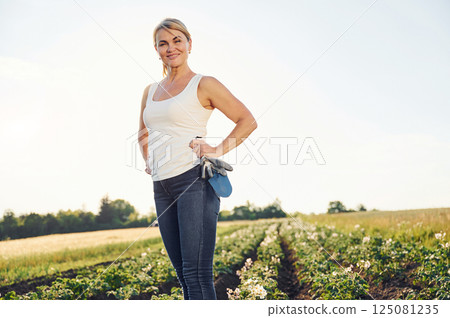 Standing in sunlight and smiling. Woman is on the agricultural field at daytime Standing in sunlight and smiling. Woman is on the agricultural field at daytime 125081235