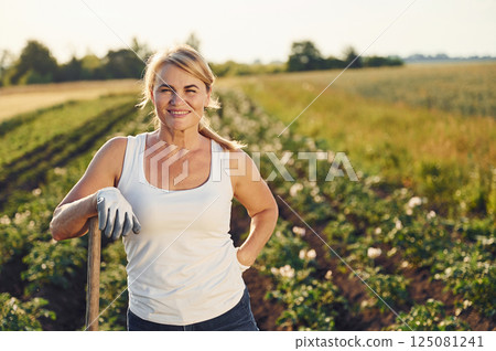 With showel in hands. Woman is on the agricultural field at daytime With showel in hands. Woman is on the agricultural field at daytime 125081241
