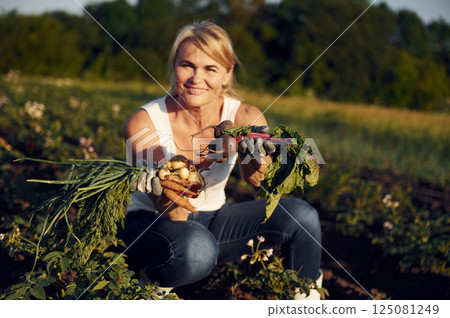 Onions, beetroots and carrots is in the hands. Woman is on the agricultural field at daytime Onions, beetroots and carrots is in the hands. Woman is on the agricultural field at daytime 125081249