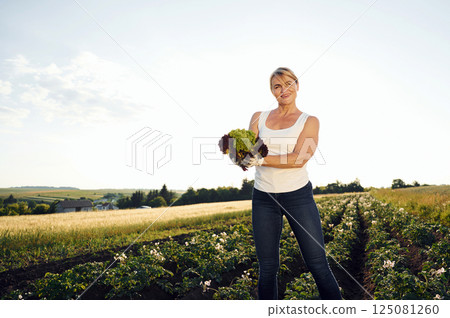 Cauliflower in hands. Woman is on the agricultural field at daytime Cauliflower in hands. Woman is on the agricultural field at daytime 125081260