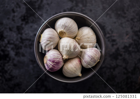 Solo glove garlic bulbs in bowl on black table. Top view. 125081331