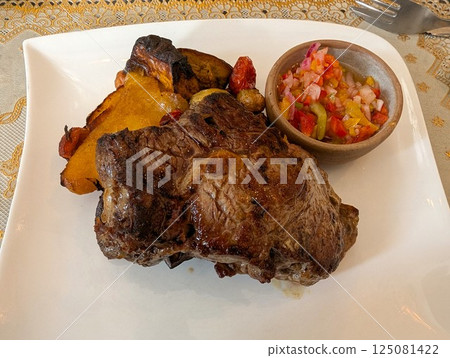 Juicy fried beef steak with grilled vegetables on a white plate and spicy vegetable sauce Juicy fried beef steak with grilled vegetables on a white plate and spicy vegetable sauce 125081422