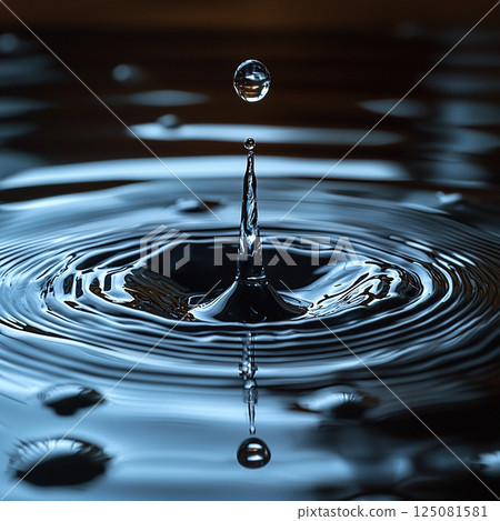 A captivating macro shot of a water droplet creating ripples upon impact and reflections. 125081581