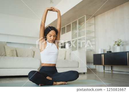 Yoga fitness workout training. Healthy African girl practicing yoga at home. Woman training Pilates doing sports exercise on yoga mat indoor. Girl have training workout for weight loss. Sport fitness 125081667