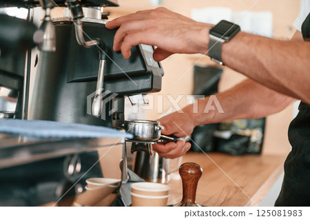 Putting raw coffee into machine to boil. Barista in the cafe. Close up view 125081983