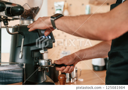 Putting raw coffee into machine to boil. Barista in the cafe. Close up view 125081984